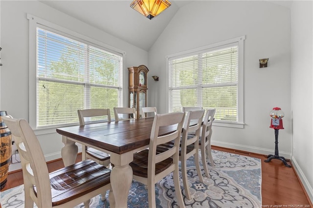 dining area featuring vaulted ceiling, wood finished floors, baseboards, and a healthy amount of sunlight