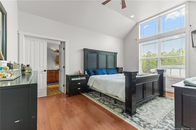 bedroom featuring a ceiling fan, light wood-style floors, connected bathroom, and vaulted ceiling