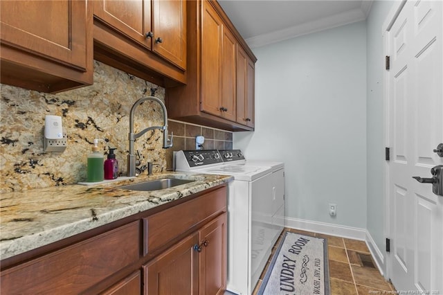laundry area with baseboards, ornamental molding, washer and dryer, a sink, and cabinet space