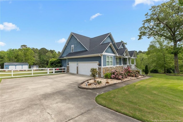 view of side of property featuring fence, an attached garage, stone siding, a yard, and concrete driveway