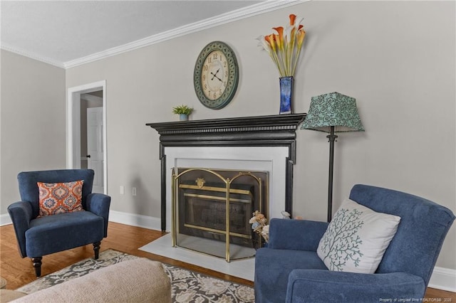 sitting room with baseboards, crown molding, a fireplace with flush hearth, and wood finished floors