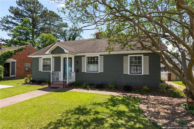 view of front of house featuring a front yard, roof with shingles, and fence