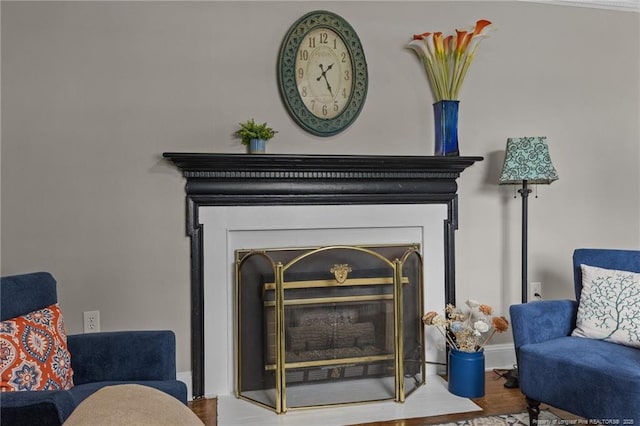 sitting room featuring baseboards, a glass covered fireplace, and wood finished floors