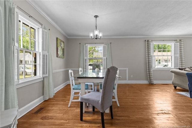 dining space with crown molding, a chandelier, wood finished floors, and a healthy amount of sunlight