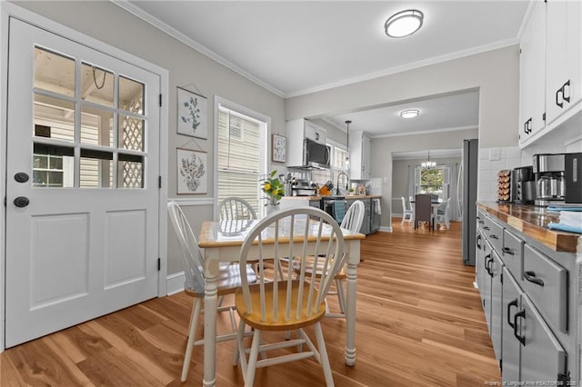 dining room with baseboards, ornamental molding, a chandelier, and light wood-type flooring