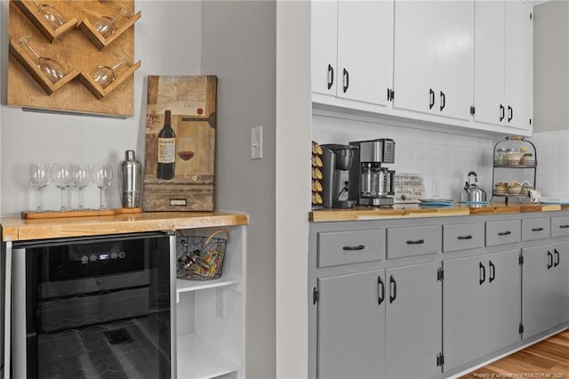 indoor dry bar featuring beverage cooler, tasteful backsplash, and wood finished floors