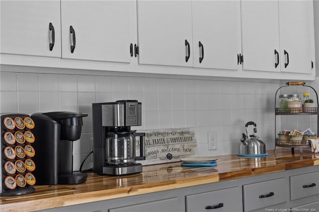 kitchen with wooden counters, white cabinets, and backsplash