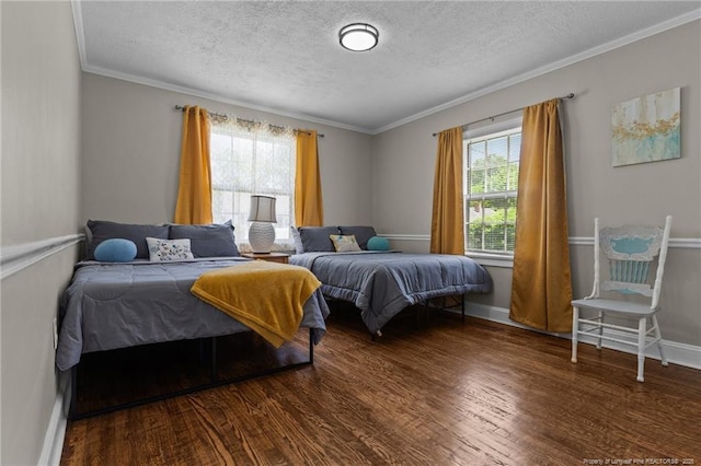 bedroom with wood finished floors, a textured ceiling, crown molding, and baseboards