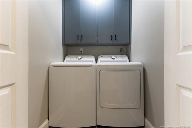 washroom with cabinet space, washing machine and dryer, and baseboards