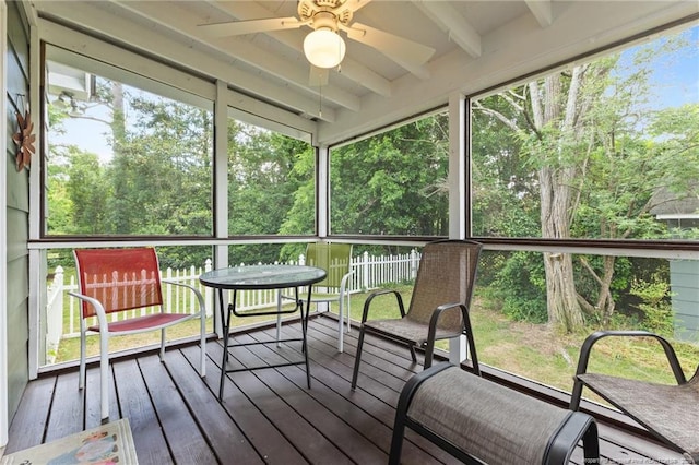 sunroom / solarium with a ceiling fan and beam ceiling