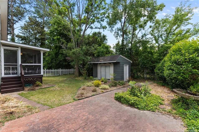 view of yard with a storage shed, a sunroom, fence, and an outbuilding