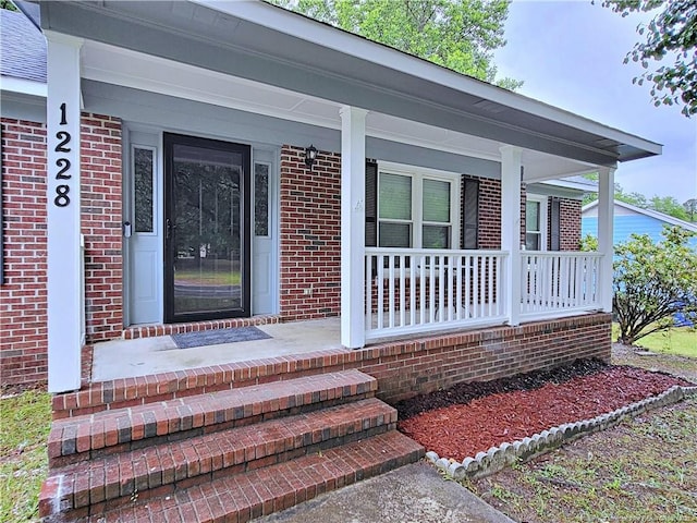 property entrance featuring a porch and brick siding