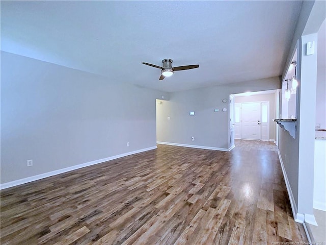 unfurnished living room with baseboards, a ceiling fan, and wood finished floors