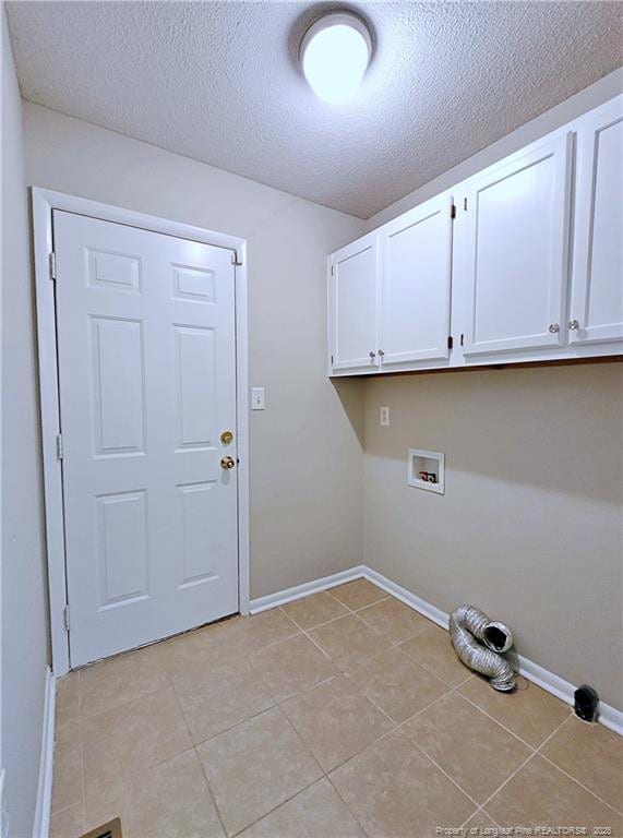 clothes washing area featuring a textured ceiling, baseboards, hookup for a washing machine, light tile patterned flooring, and cabinet space