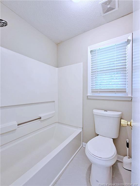 bathroom with toilet, tile patterned floors, a textured ceiling, visible vents, and baseboards