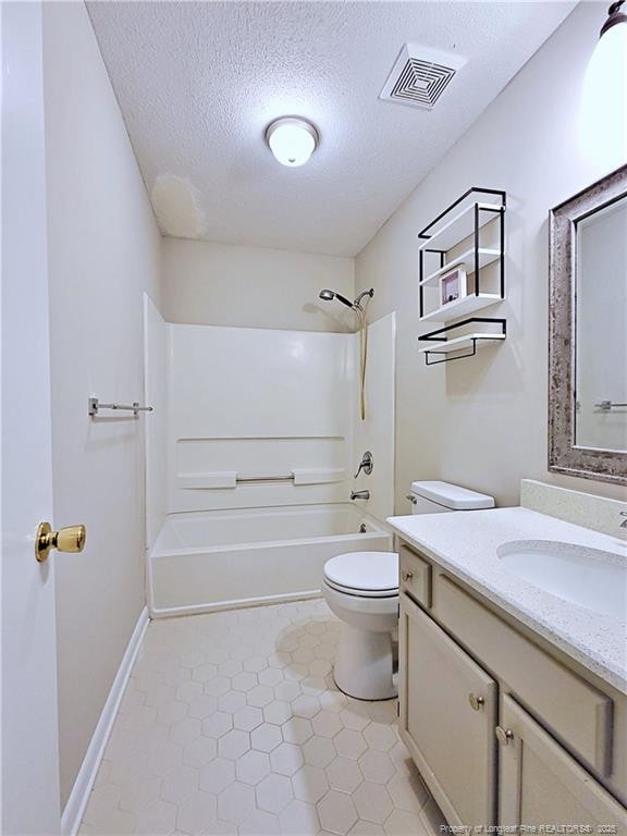 bathroom with toilet, vanity, a textured ceiling, visible vents, and bathtub / shower combination