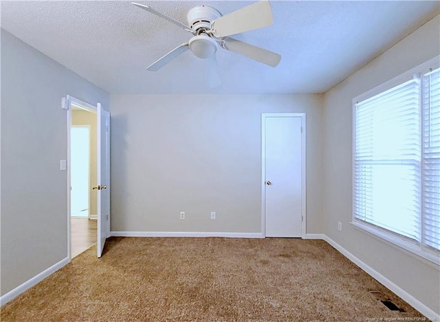 empty room with carpet flooring, baseboards, a ceiling fan, and plenty of natural light