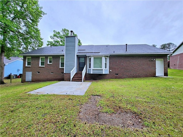 rear view of property with a patio, crawl space, a chimney, a yard, and brick siding