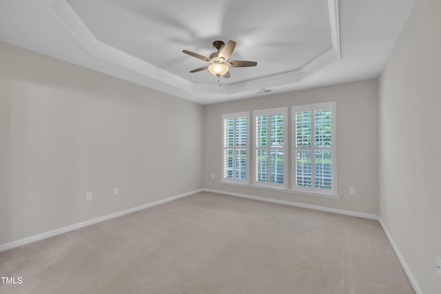 unfurnished room featuring a raised ceiling, a ceiling fan, light colored carpet, and baseboards