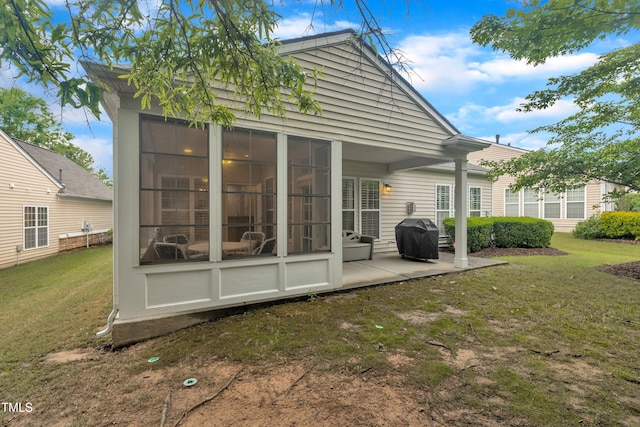 rear view of house with a patio area, a lawn, and a sunroom