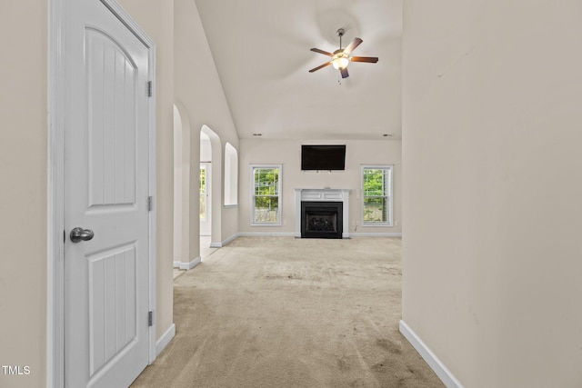309 Coachmans Trl, Stem, NC 27581 - unfurnished living room with carpet flooring, a ceiling fan, baseboards, arched walkways, and a fireplace with flush hearth