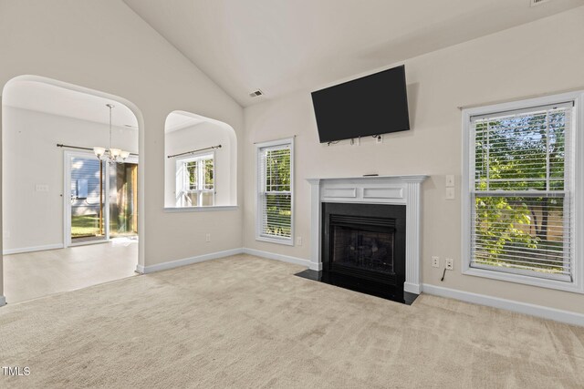 309 Coachmans Trl, Stem, NC 27581 - unfurnished living room featuring a chandelier, carpet flooring, baseboards, a fireplace with flush hearth, and vaulted ceiling