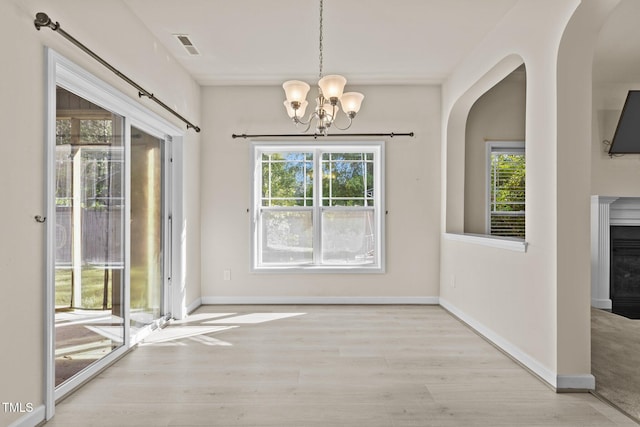 309 Coachmans Trl, Stem, NC 27581 - unfurnished dining area featuring arched walkways, a chandelier, wood finished floors, and healthy amount of natural light