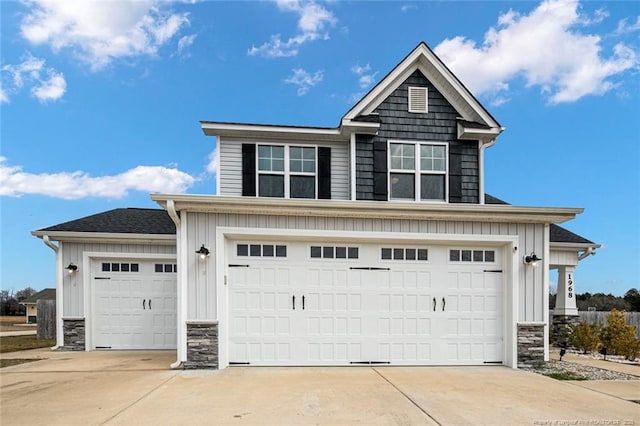 view of front of house with board and batten siding, stone siding, driveway, and an attached garage