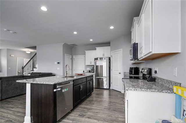 kitchen with appliances with stainless steel finishes, a sink, white cabinets, open floor plan, and dark wood-style flooring