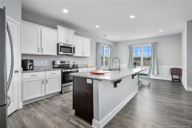 kitchen featuring appliances with stainless steel finishes, a sink, a kitchen island with sink, dark wood-style flooring, and recessed lighting