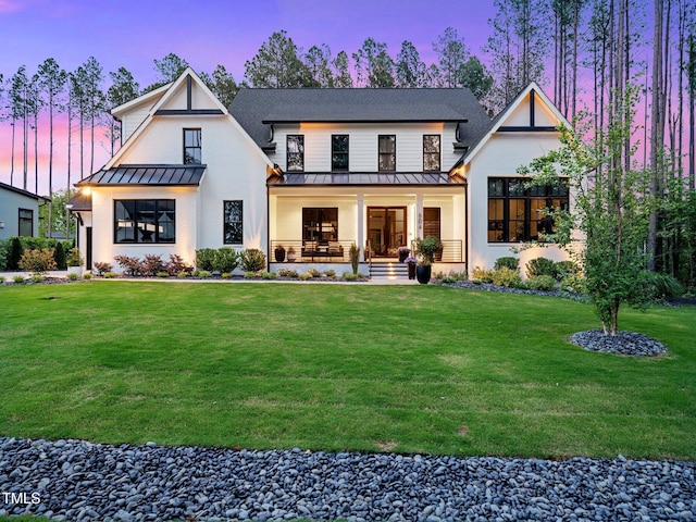 604 Dappled Pine Ave, Durham, NC 27713 - back of property at dusk featuring a standing seam roof, covered porch, a lawn, and metal roof