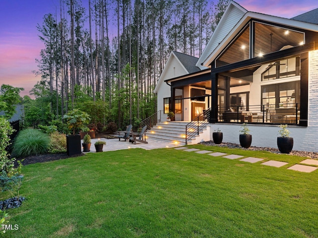 604 Dappled Pine Ave, Durham, NC 27713 - back of property at dusk featuring a lawn and a patio area