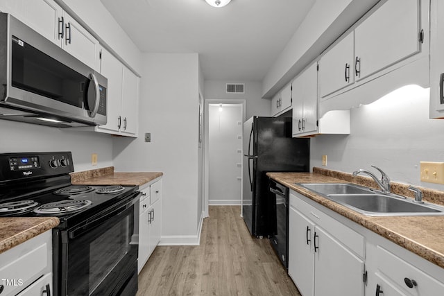 1131 Schaub Dr, Raleigh, NC 27606 - kitchen with black appliances, a sink, light wood-type flooring, white cabinets, and baseboards