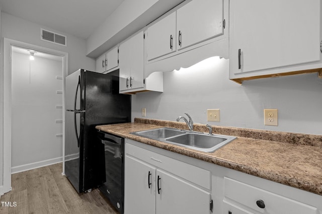 1131 Schaub Dr, Raleigh, NC 27606 - kitchen with a sink, black appliances, light wood-style flooring, and white cabinets