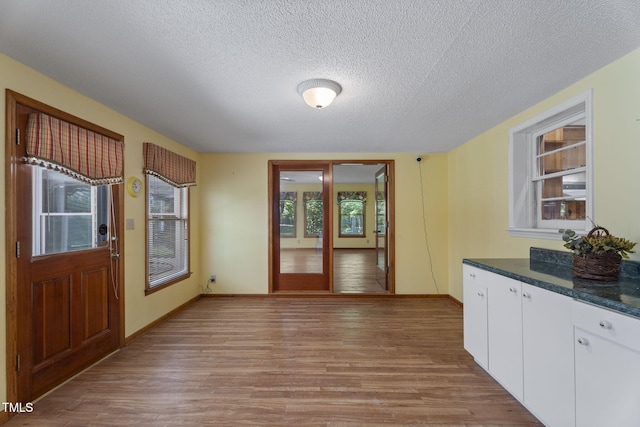 5517 Spring Rd, Raleigh, NC 27603 - unfurnished dining area featuring light wood-type flooring, a textured ceiling, and baseboards