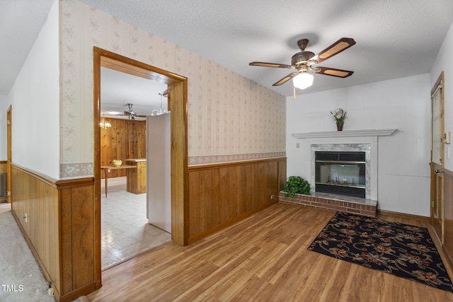 5517 Spring Rd, Raleigh, NC 27603 - unfurnished living room featuring wallpapered walls, wood finished floors, wainscoting, a ceiling fan, and a glass covered fireplace