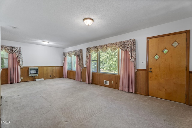 5517 Spring Rd, Raleigh, NC 27603 - unfurnished living room featuring wainscoting, heating unit, wood walls, carpet flooring, and a textured ceiling