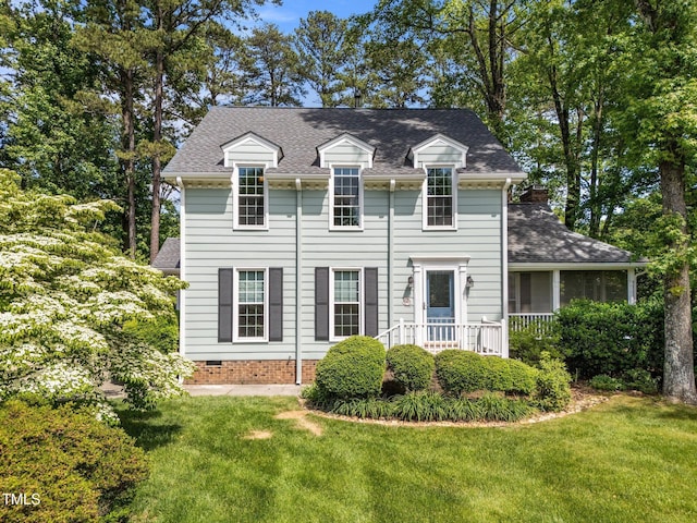 view of front facade featuring a front lawn, a shingled roof, and a chimney