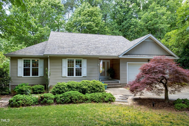 view of front facade with an attached garage, roof with shingles, and a front yard