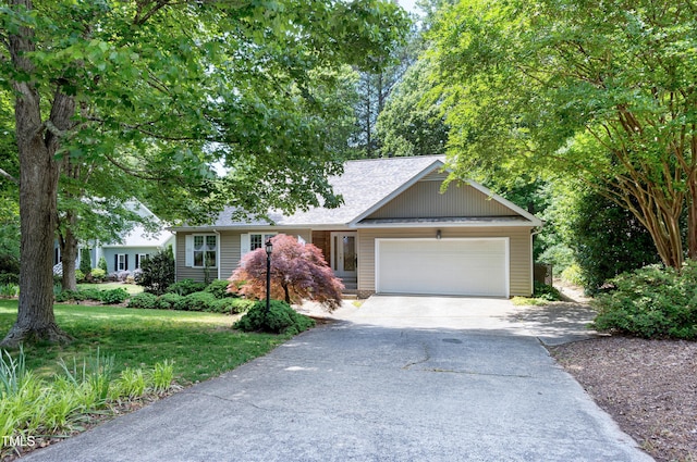 view of front of house with driveway, an attached garage, roof with shingles, and a front yard