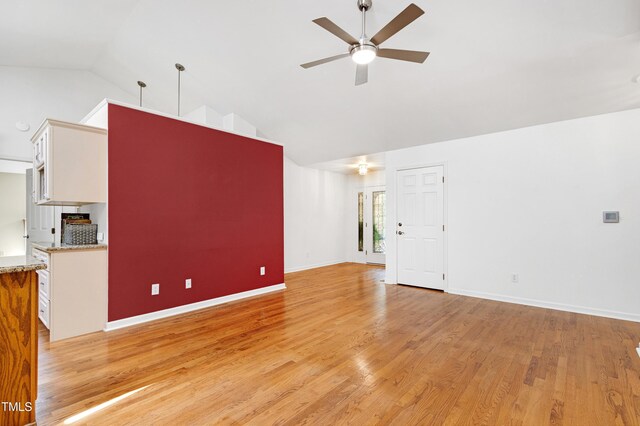 unfurnished living room featuring ceiling fan, high vaulted ceiling, light wood finished floors, and baseboards