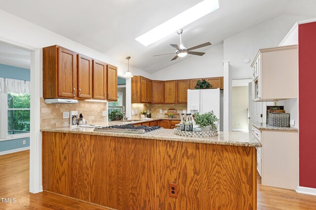 kitchen featuring white fridge with ice dispenser, stainless steel gas cooktop, lofted ceiling, light wood-type flooring, and brown cabinets