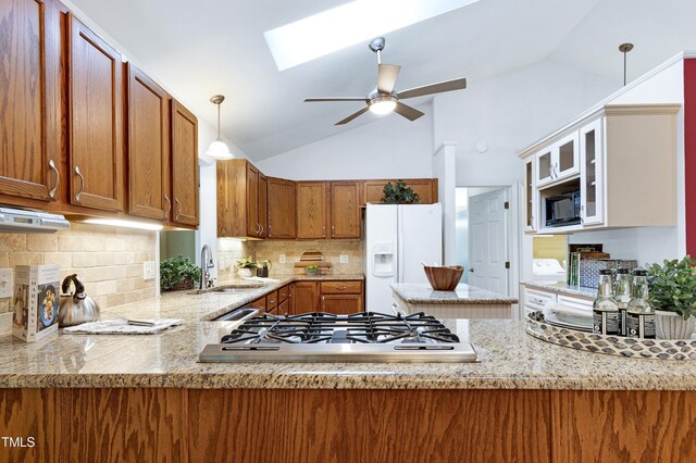 kitchen featuring stainless steel gas cooktop, white refrigerator with ice dispenser, a sink, brown cabinets, and ceiling fan