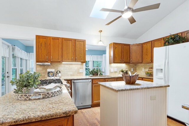 kitchen with white refrigerator with ice dispenser, stainless steel dishwasher, a sink, a skylight, and light wood-style flooring