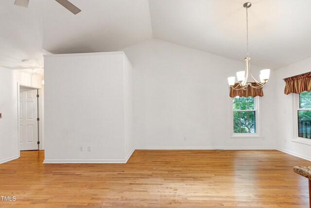 empty room featuring a chandelier, lofted ceiling, light wood finished floors, a ceiling fan, and baseboards