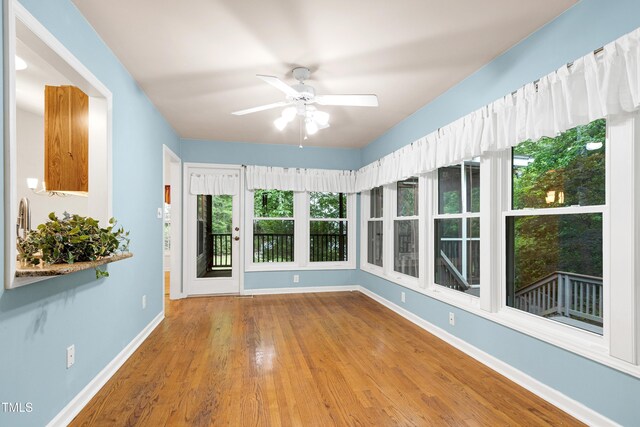 unfurnished sunroom featuring baseboards and wood finished floors
