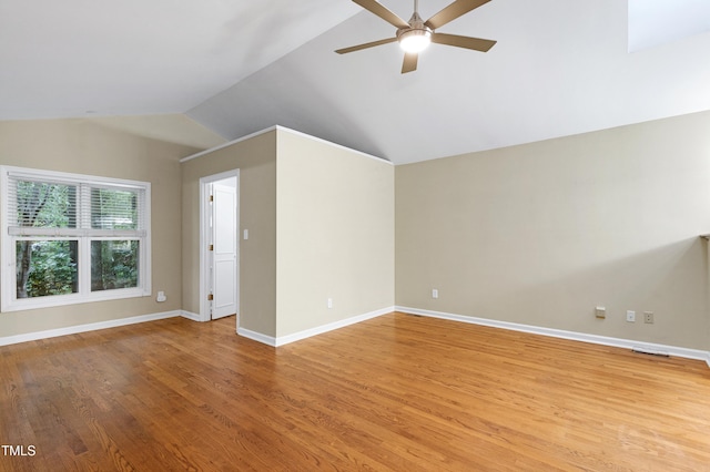spare room featuring vaulted ceiling, ceiling fan, light wood-style flooring, and baseboards