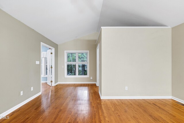 spare room with wood finished floors, vaulted ceiling, and baseboards