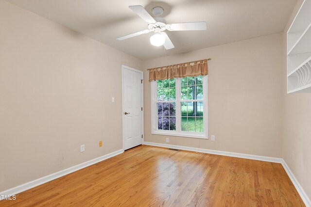 spare room with baseboards, light wood-type flooring, and ceiling fan
