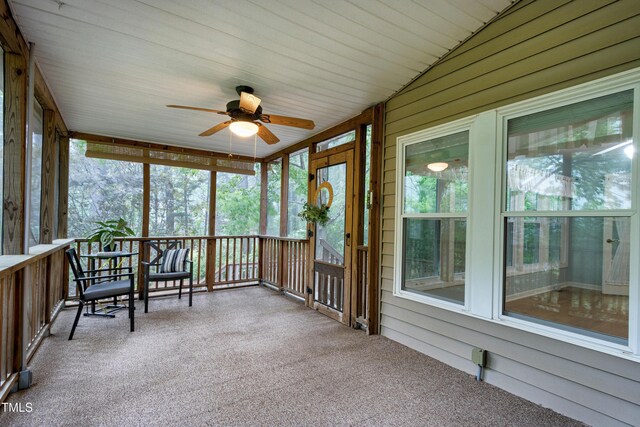 sunroom / solarium featuring a ceiling fan, healthy amount of natural light, and vaulted ceiling
